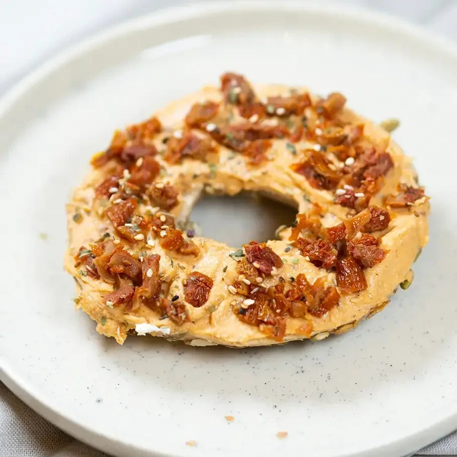 halber Bagels mit würzigem Hummus und getrockneter Tomate.