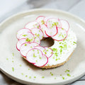 halber Bagel mit Frischkäse, Radieschen und Schnittlauch.