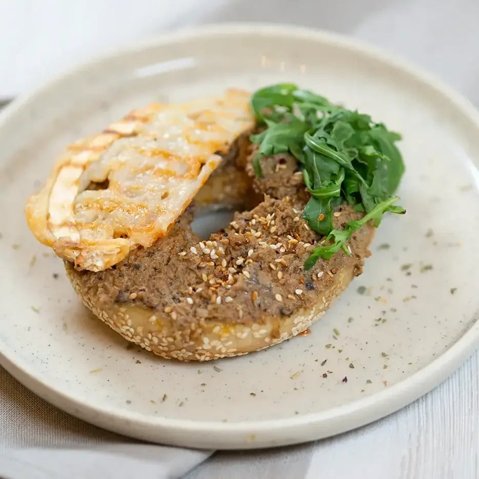 halber Bagel mit Auberginencreme, Ziegenkäse und Salat.