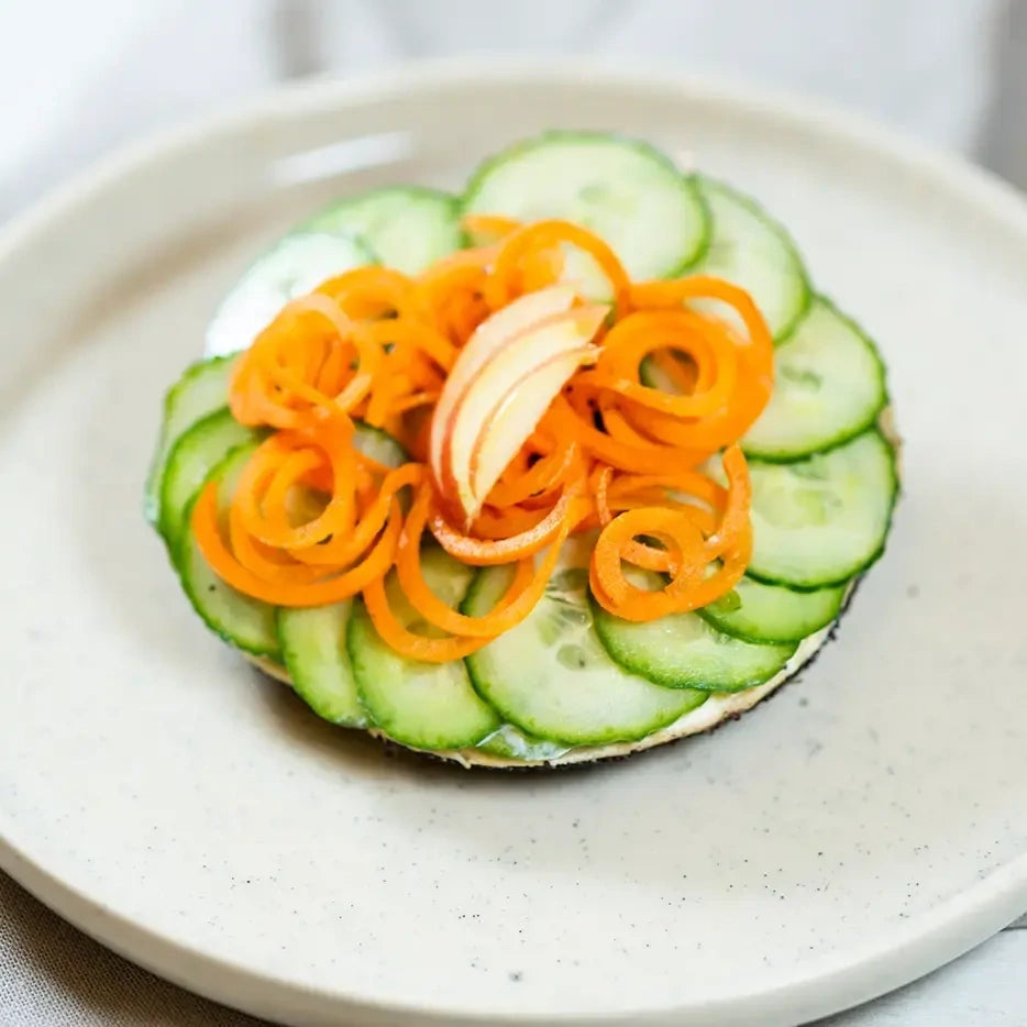 halber Bagel mit Karotten, Gurke, Apfel und Maracuja Dressing.