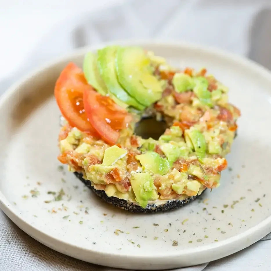 halber Bagel mit  Avocadosmash, Tomate verfeinert mit Zitrone und Minze.