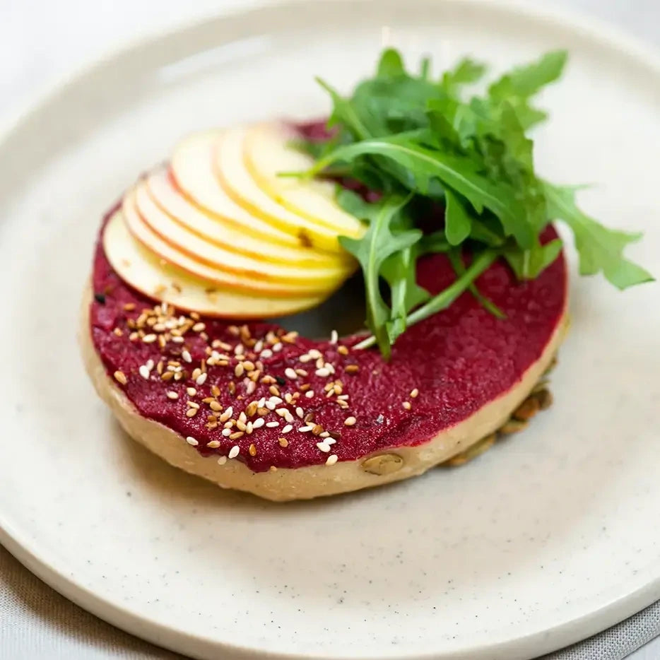 halber Bagel mit  leichtem Rote Beete Pate, Apfel, Rucola und gerösteten Kürbiskernen.