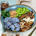 Bowle mit geröstetem Blumenkohl, Pilzen, Hummus, Couscous, Edamame, Minze, Walnüssen und Feta.