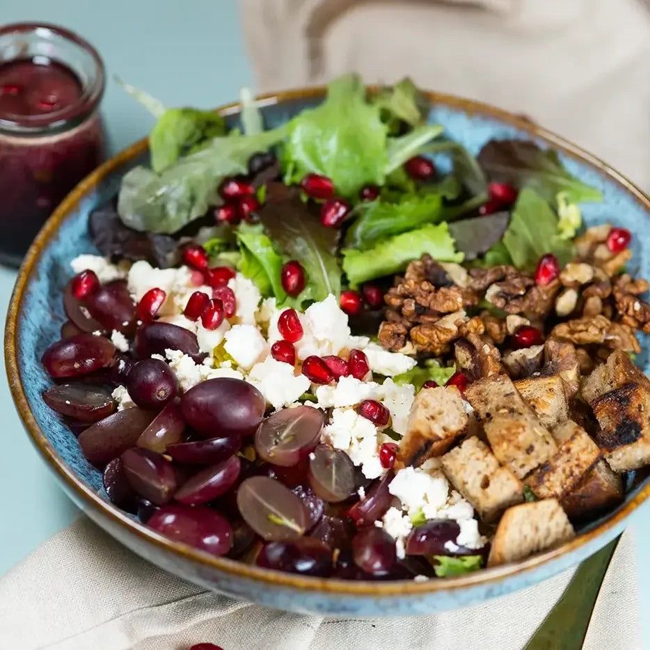 Bowle Salate mit Blattsalat, Weintrauben, Walnüsse, Feta, hausgemachten Kräuter-Croutons, Waldbeeren und Walnuss Dressing.