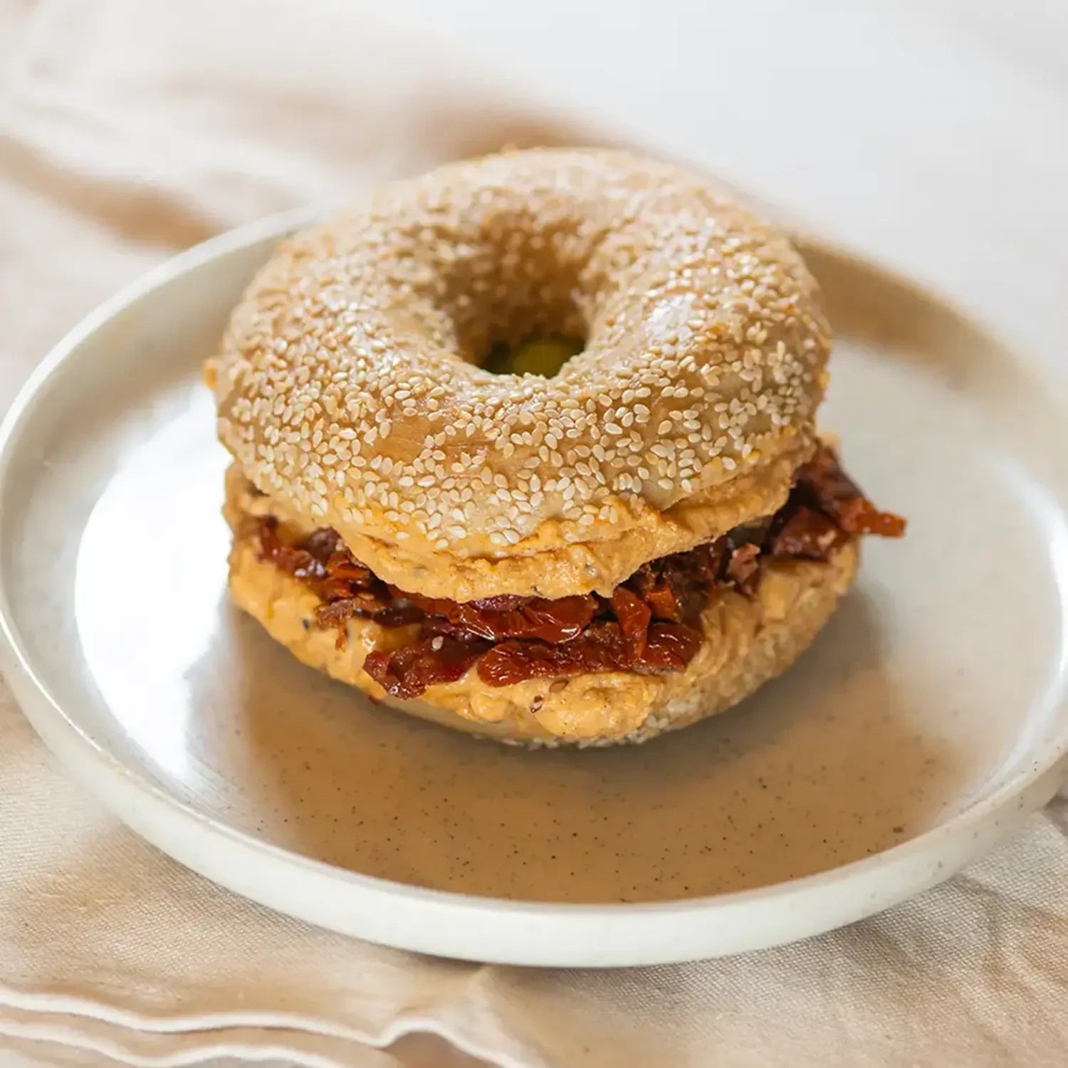 ganzer Bagel mit hausgemachten würzigem Hummus und getrockneter Tomate.