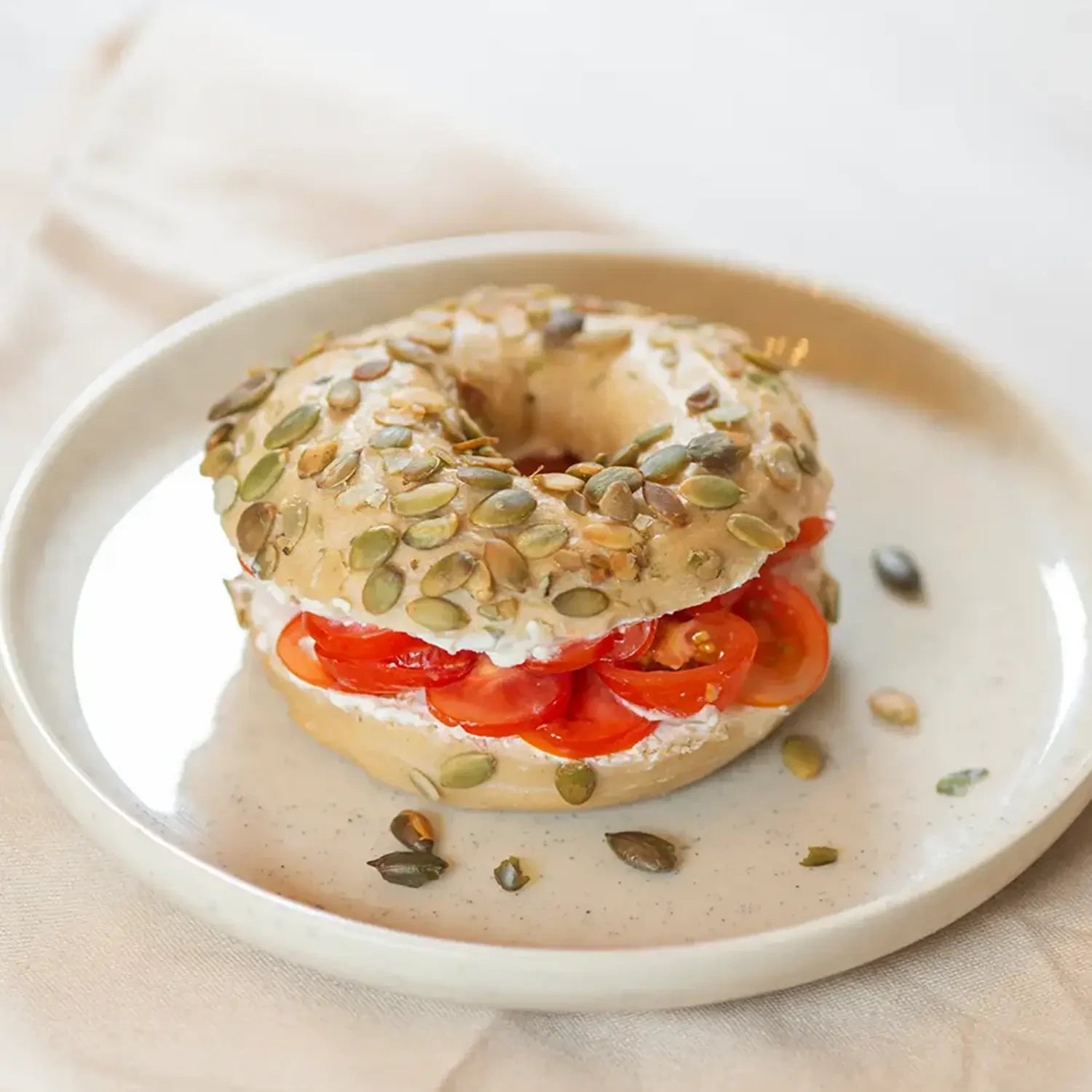 ganzer Bagel mit Frischkäse und Tomate.