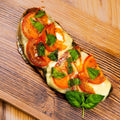 Sandwich mit überbackener Mozzarella, Basilikumpesto, frischen Tomate und Basilikum.