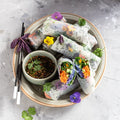 Fingerfood Sommerrollen mit Tofu, rotem Reis, Minze, Avocado, Gurke, essbaren Blumen und Erdnuss-Hoisin-Sauce- 10 Stück