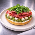 halber Bagel mit Pesto, Feta, italienischer Salami und Ruccola
