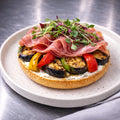 halber Bagel mit Proscuitto, gegrillter Aubergine und Paprika