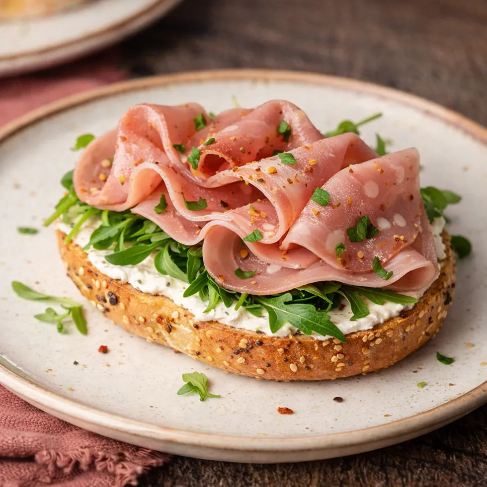 halber Bagel mit Riccota, Mortadella und Ruccola